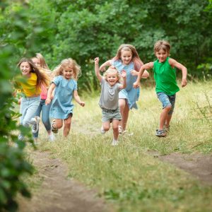 Kids, children running on green meadow, forest