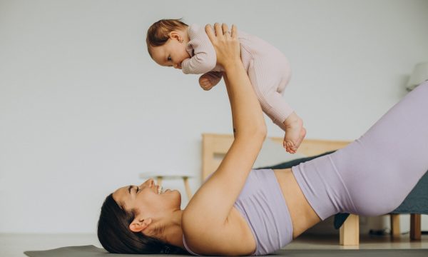 Mother with her baby daughter practice yoga at home